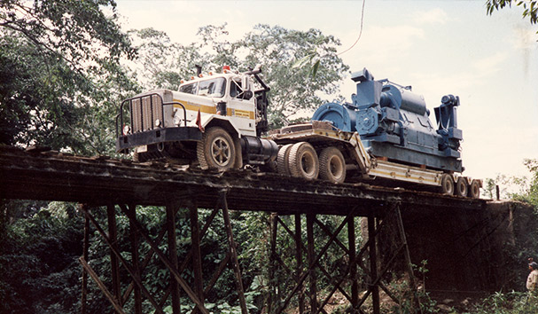 Camión transportando maquinaria pesada sobre un puente de madera en una zona rural, demostrando la capacidad de Repetto para operar en terrenos difíciles.